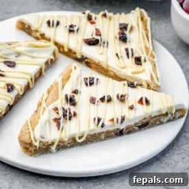 Three bliss bars on a white plate with white chocolate drizzle and cranberries.