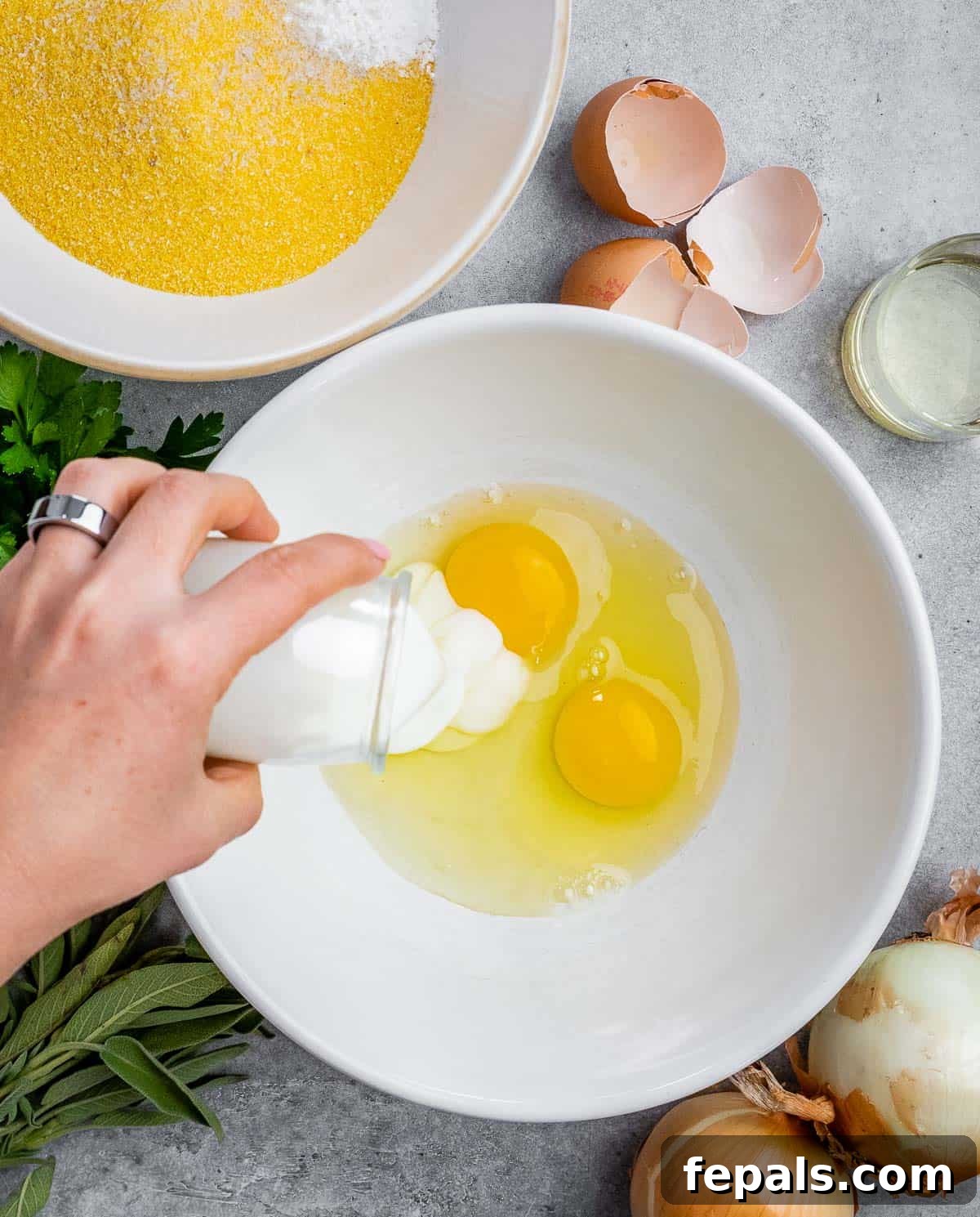 Whisking wet ingredients for cornbread in a large white bowl.