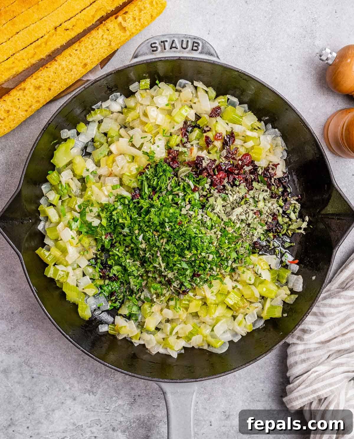 Sautéing diced onion and chopped celery in a large skillet on the stovetop.