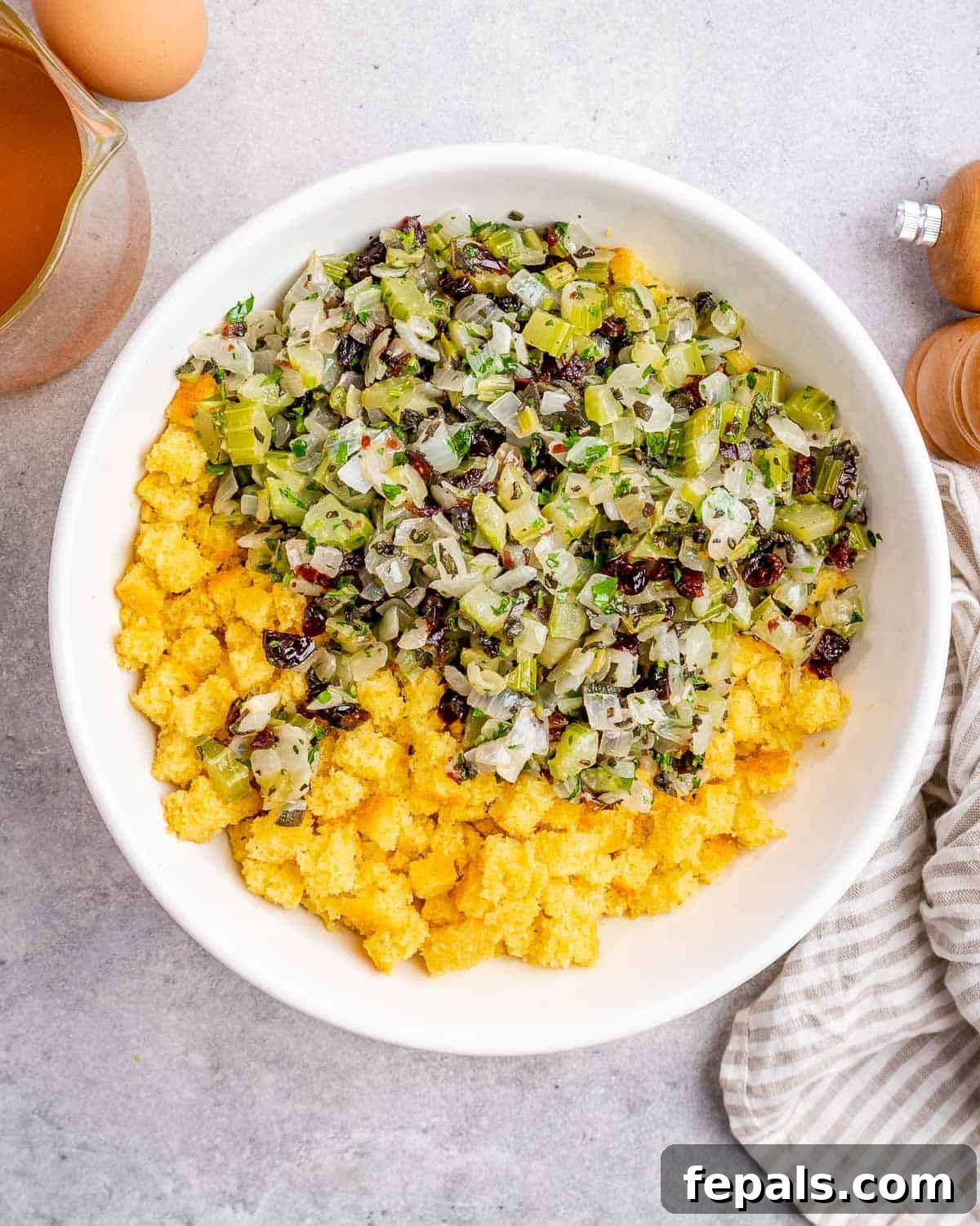 Mixing sautéed vegetables and herbs with crumbled cornbread in a very large bowl.