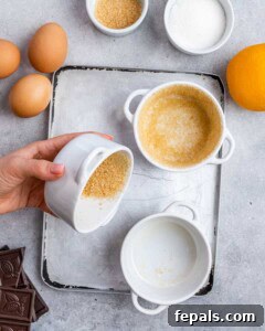 Hand coating the inside of a white ramekin with brown sugar after spraying it with oil, preparing it for baking.