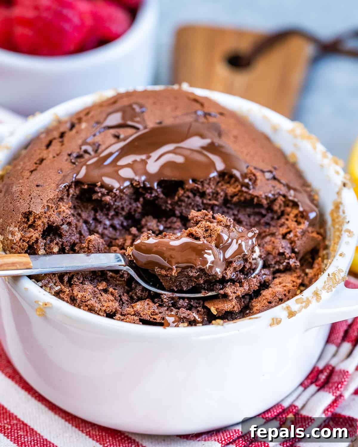 Close-up of a spoonful of warm Chocolate Soufflé being lifted, showing its rich, mousse-like interior, with melted chocolate and fine sugar dust on top.