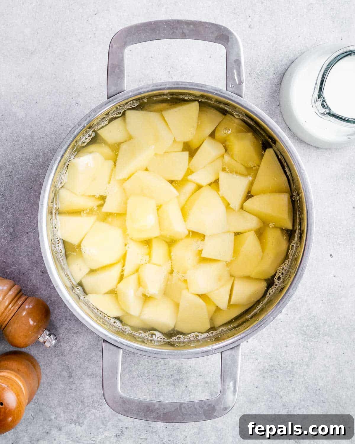 Cubed potatoes boiling gently in a large soup pot, ready for mashing.