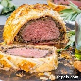 Regal Beef Wellington 12 Sliced beef wellington on a cutting board, showing layers of pastry, prosciutto, duxelles, and perfectly cooked beef.