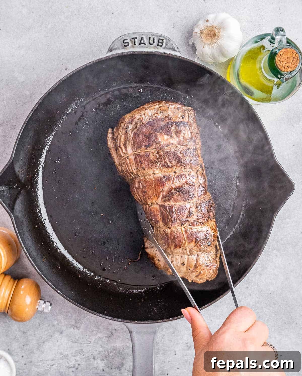 Regal Beef Wellington 5 A beef tenderloin being seared to a golden brown on all sides in a hot pan.