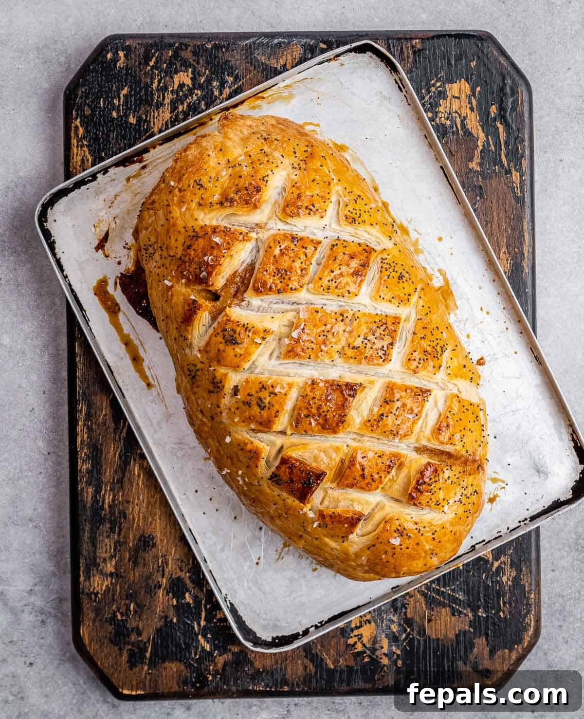 Regal Beef Wellington 8 A freshly baked Beef Wellington, golden brown and perfectly cooked, resting on a sheet pan after coming out of the oven.