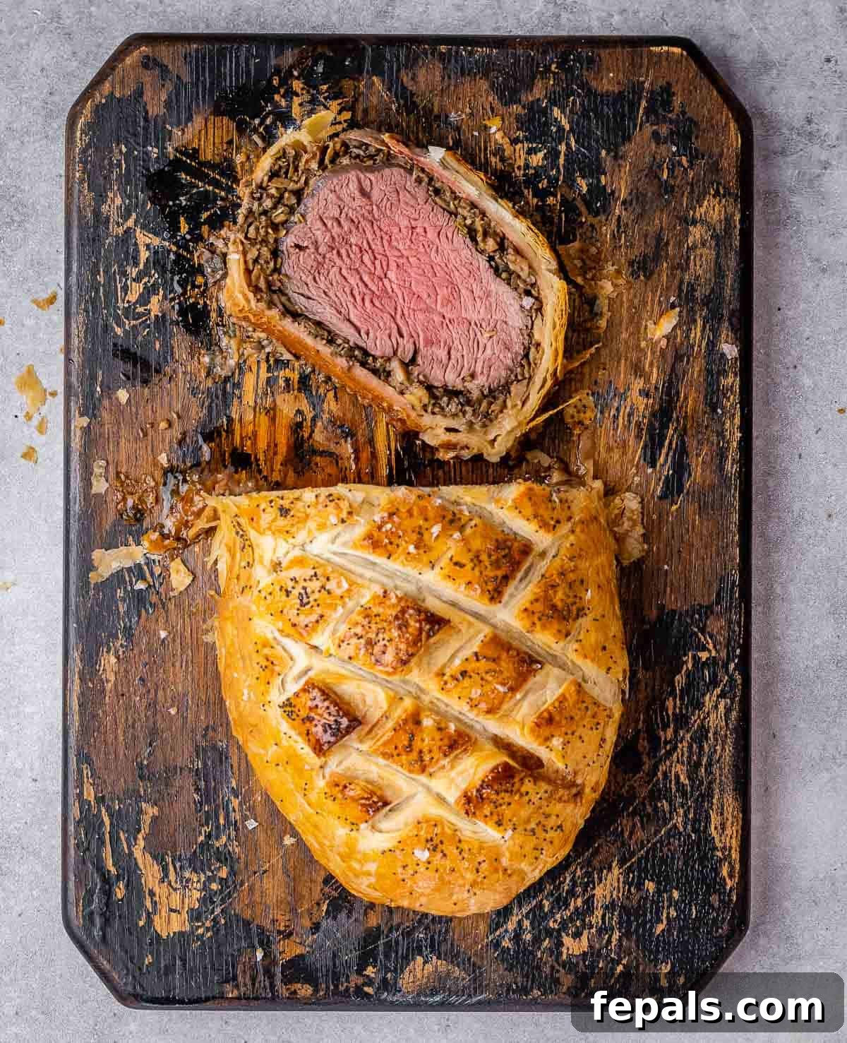 Regal Beef Wellington 10 A close-up of a beautifully sliced Beef Wellington on a wooden cutting board, showcasing the tender beef and flaky pastry.