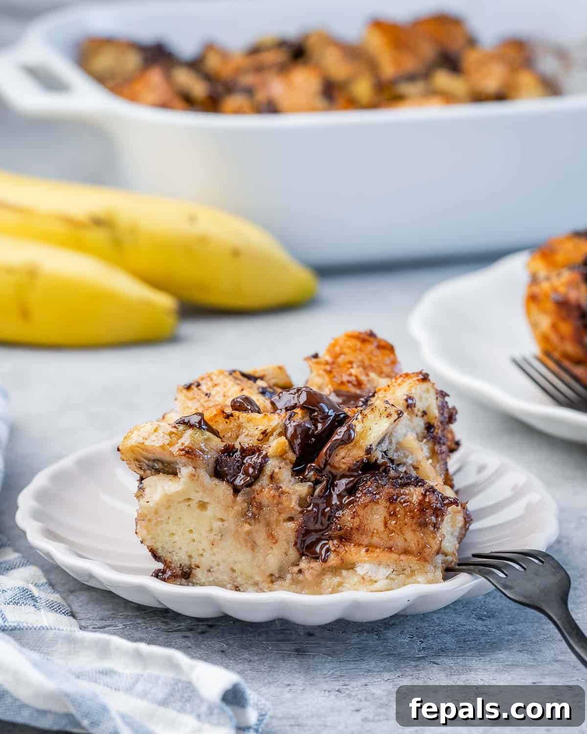 A perfectly baked slice of banana bread pudding, showing its custardy interior and crispy edges, presented on a clean white plate, ready to eat.