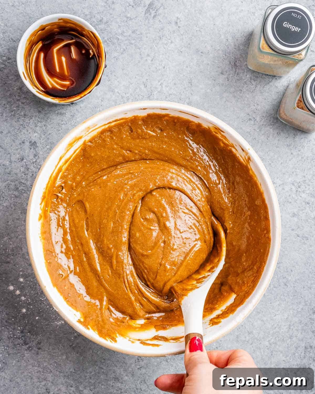 gingerbread batter in a bowl with spoon mixing the batter.