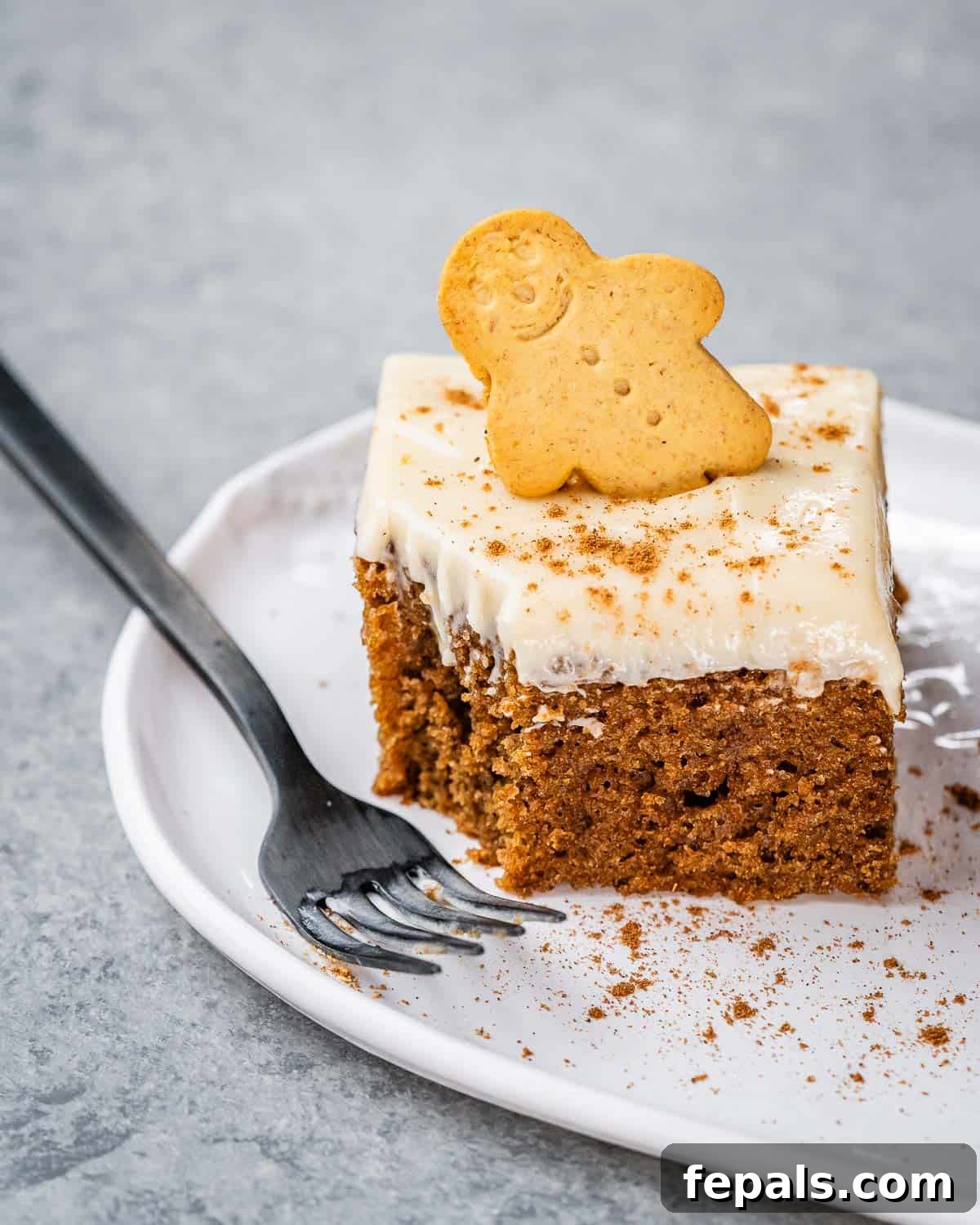 a single gingerbread square cake on a plate with a fork taken a bite off it.