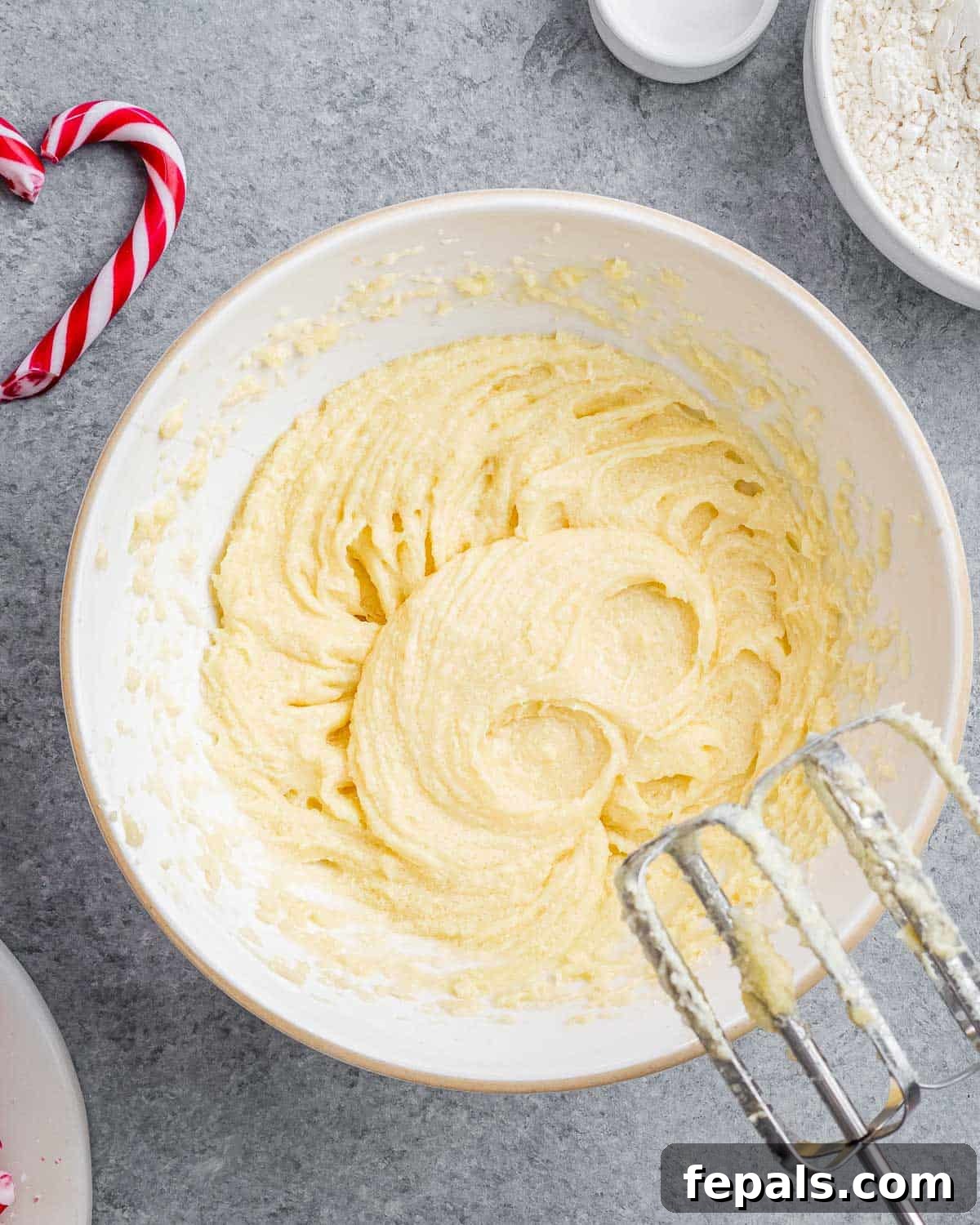 Creamy butter, sugar, and egg mixture being whipped to perfection in a bowl with an electric mixer, becoming light and fluffy.