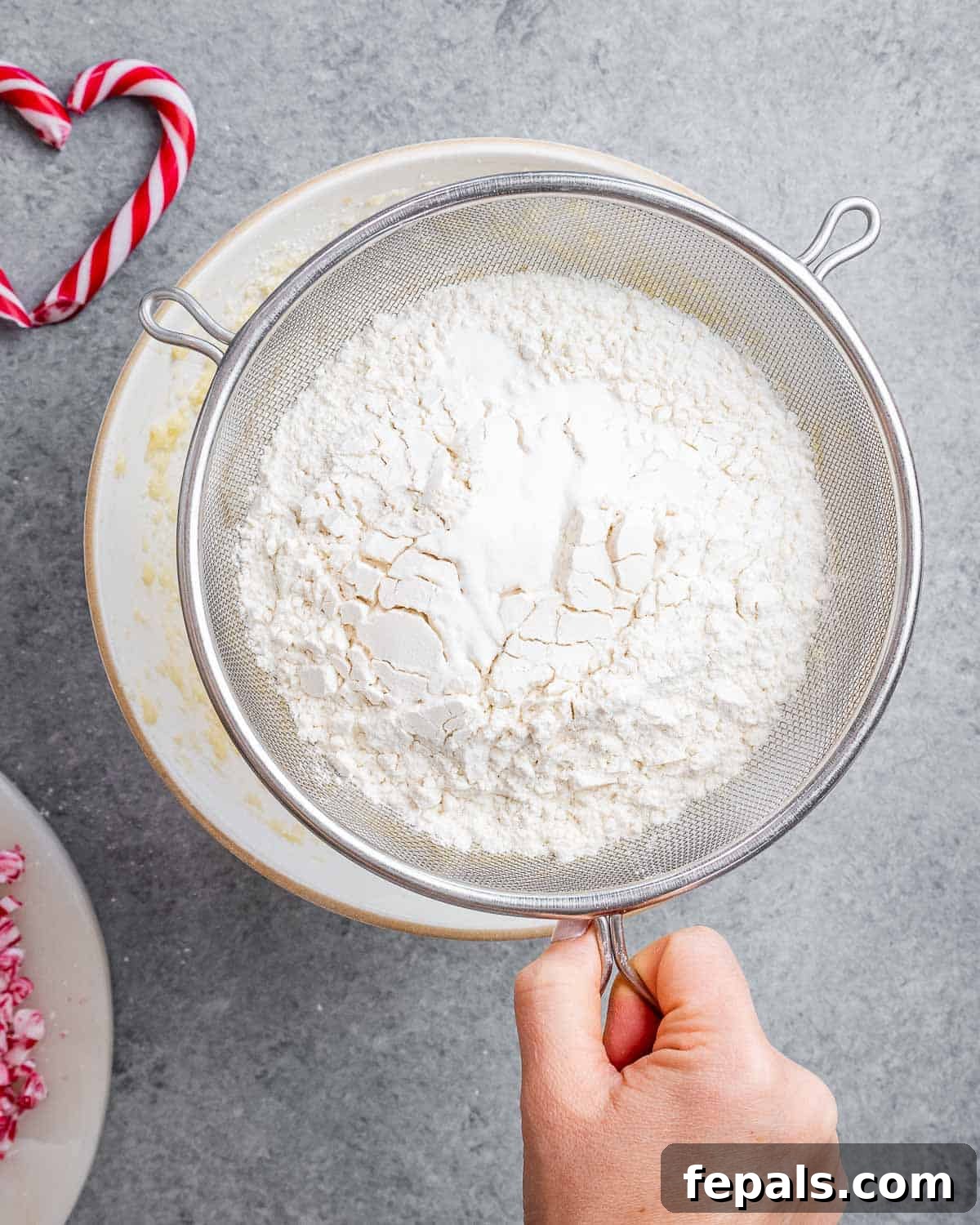 All-purpose flour and baking soda being carefully sifted into a separate bowl, ensuring a smooth, lump-free dry mixture for cookie dough.