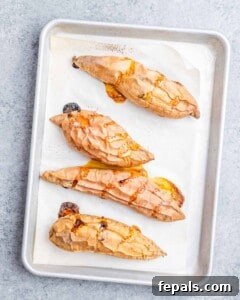 Baked sweet potatoes on a sheet pan, caramelized and soft, fresh from the oven.