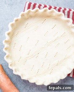 Raw pie crust in a dish with fork holes pricked into the bottom, ready for filling.