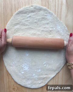 Dough being rolled out on a flat cutting board.