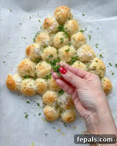parsley and parmesan cheese being garnished over the baked cheese ball tree.