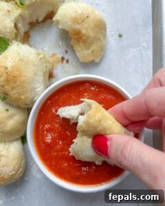 cheese ball bread being dipped in marinara sauce.
