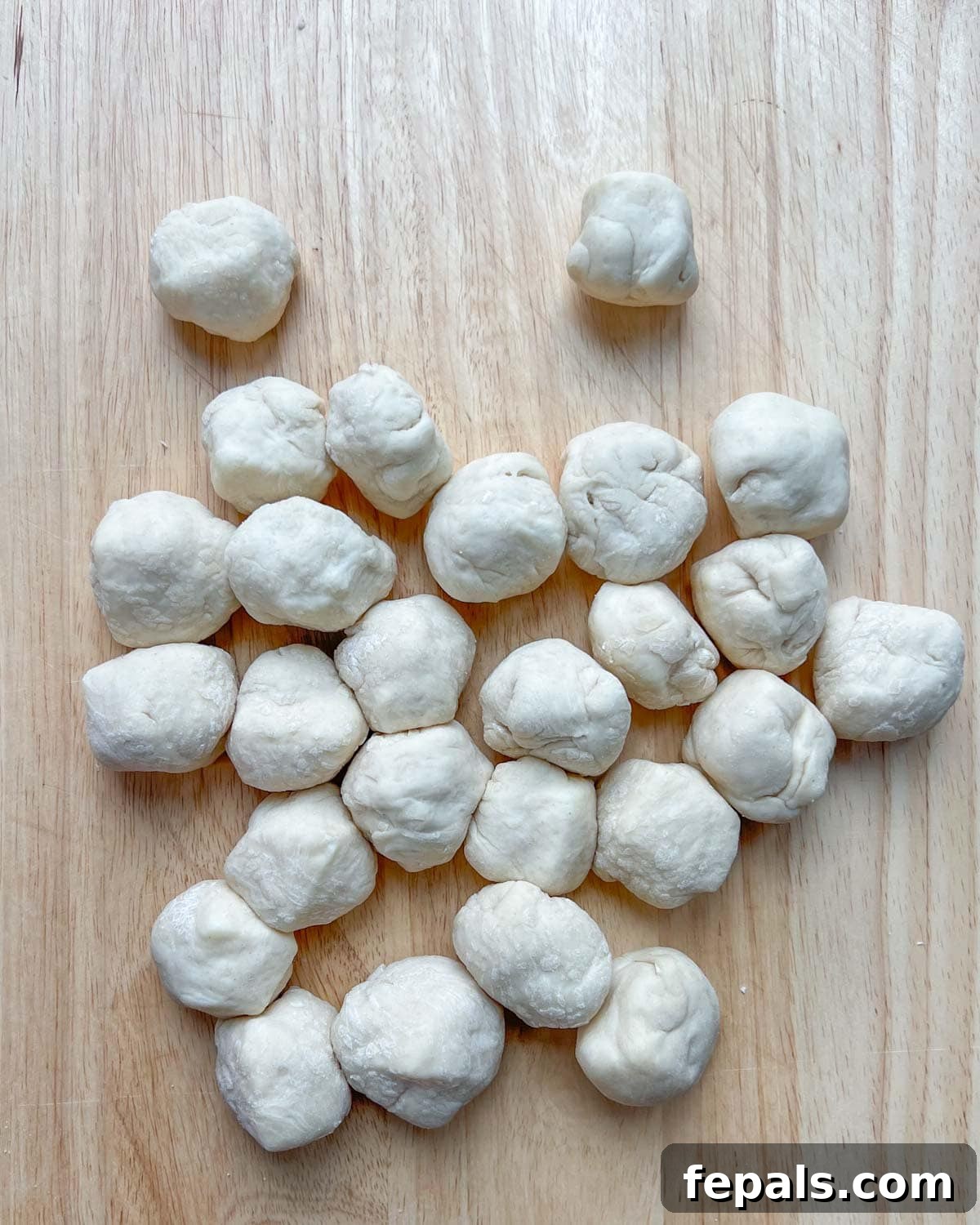 Individual dough squares meticulously stuffed with mozzarella cheese and sealed into neat, round balls.