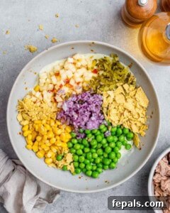 The McConaughey Tuna Salad That Broke the Internet 12 Neatly arranged chopped ingredients including peas, corn, red onion, apple, and pickles before mixing.