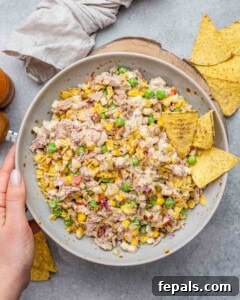 The McConaughey Tuna Salad That Broke the Internet 14 Hands holding a bowl of finished tuna salad with visible peas, corn, red onion, and chips.