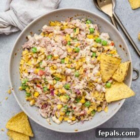 A round bowl with tuna salad and two tortilla chips in it.