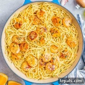 Overhead shot of scallop spaghetti served in a wide skillet, garnished with fresh herbs.