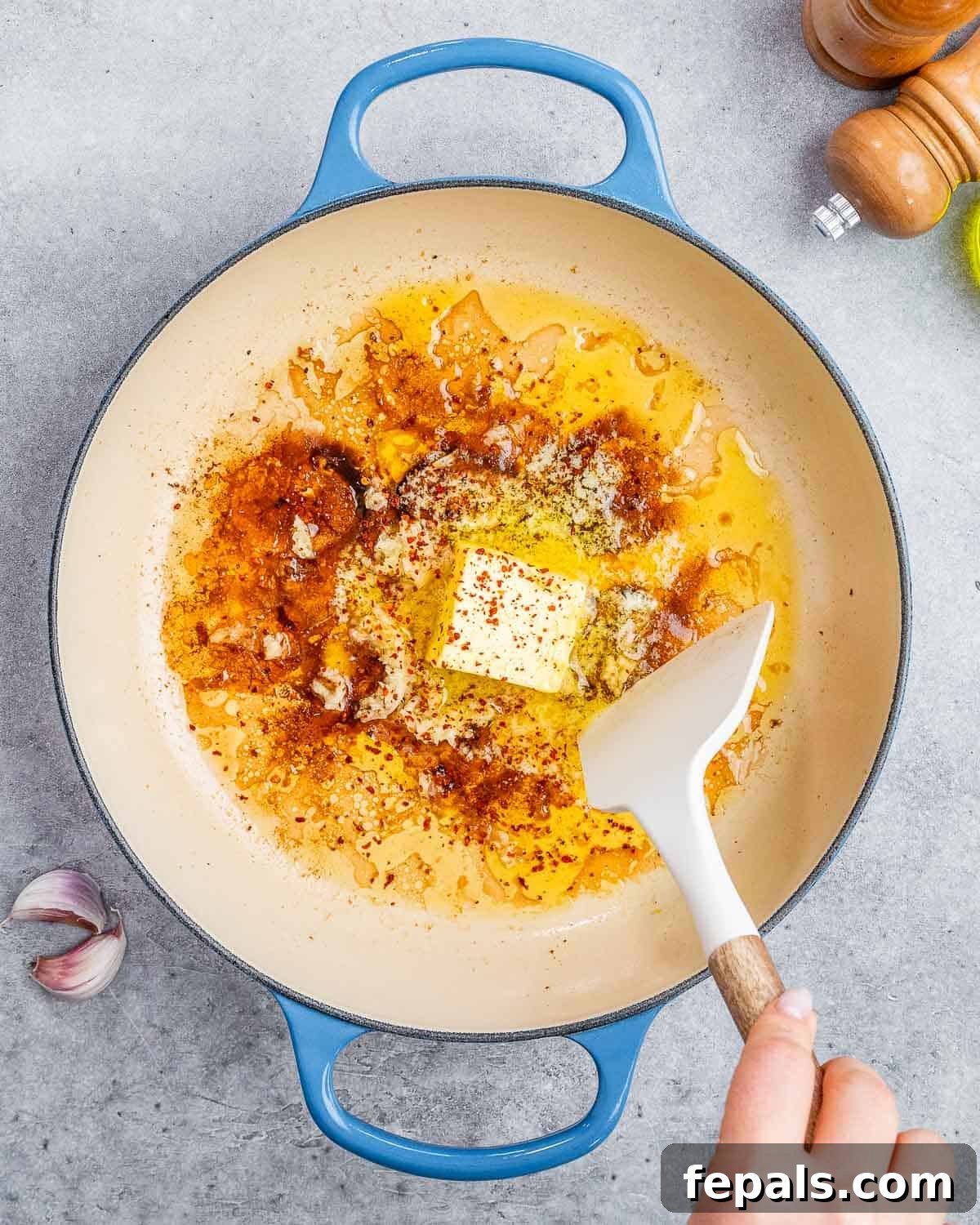 Minced garlic, rich butter, and crushed chili flakes melting together in a hot skillet, forming the fragrant base for the scallop pasta sauce.