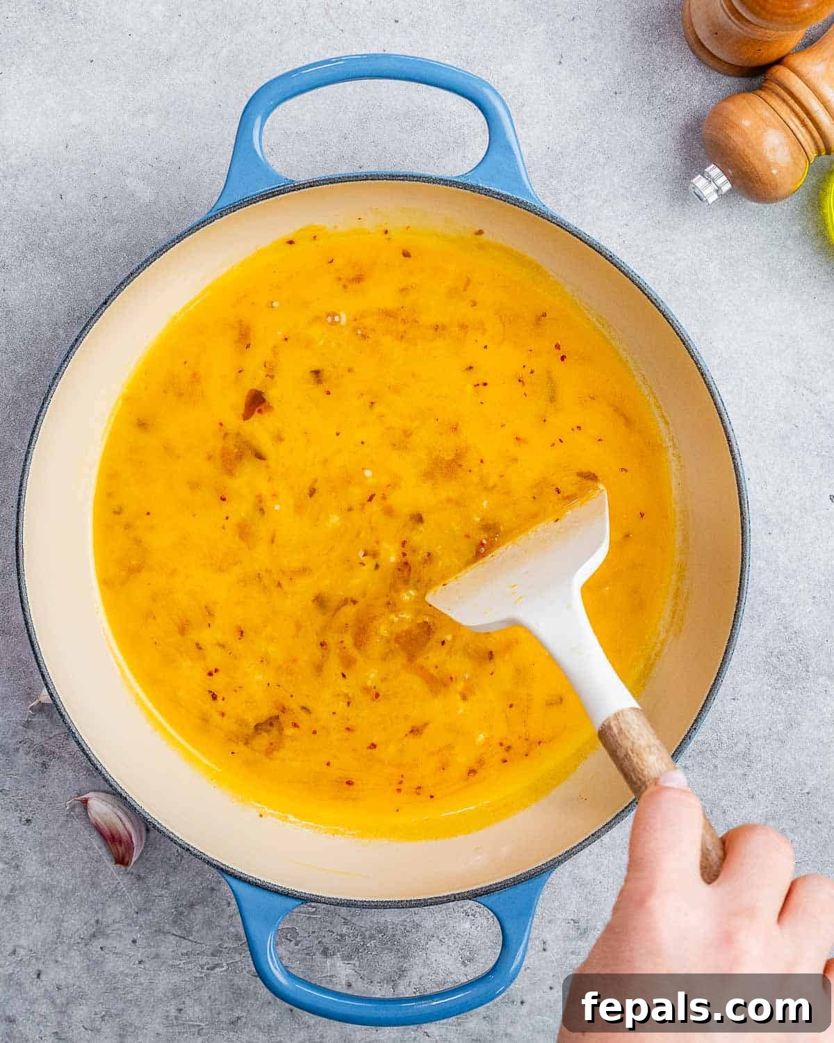 A smooth, glossy citrus garlic sauce being whisked vigorously in the skillet after deglazing, ready to coat the pasta and scallops.