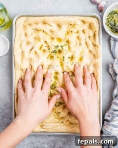 Perfect Italian Focaccia At Home 16 Making dimples in focaccia bread dough recipe with olive oil and fresh rosemary.