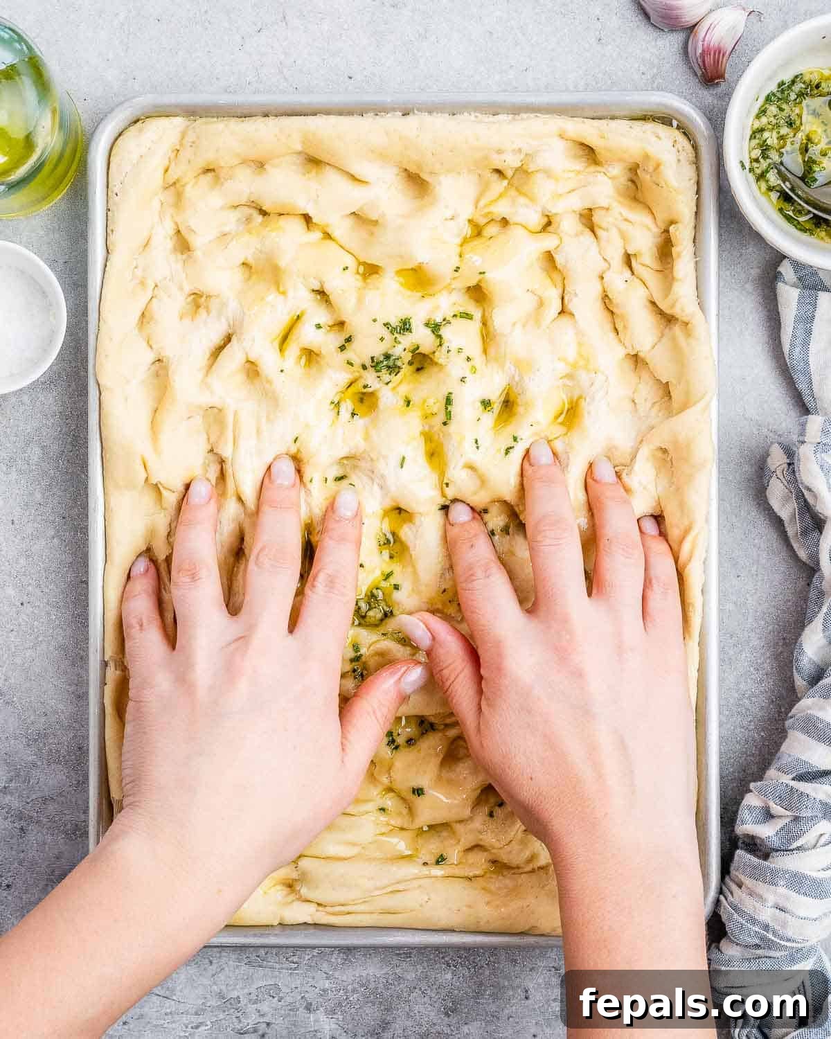 Perfect Italian Focaccia At Home 7 Creating dimples in focaccia dough with olive oil and rosemary.