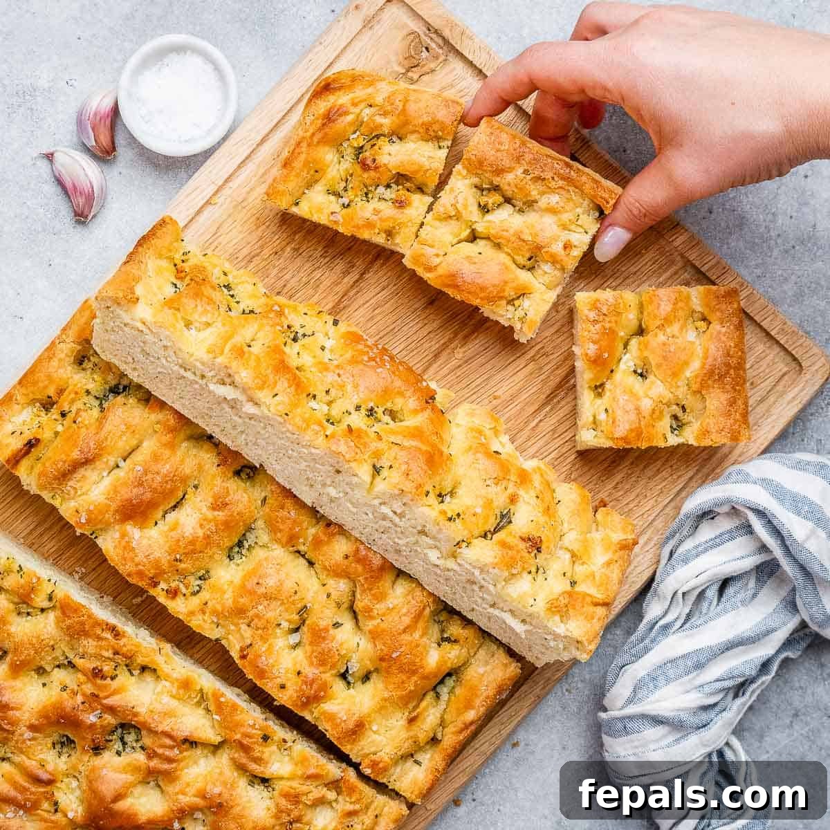 Perfect Italian Focaccia At Home 10 Sliced focaccia on a cutting board, garnished with rosemary.