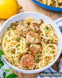 A white bowl filled with spaghetti pasta and topped with chicken meatballs.