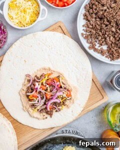 Hummus, sausage, onions, tomatoes on a large flour tortilla.