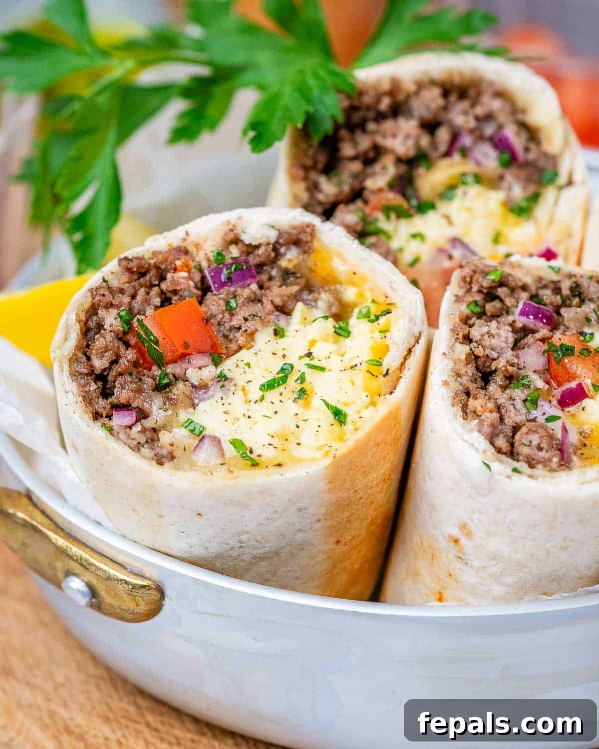 Three halves of a breakfast burrito standing up to show the ingredients on a white plate.