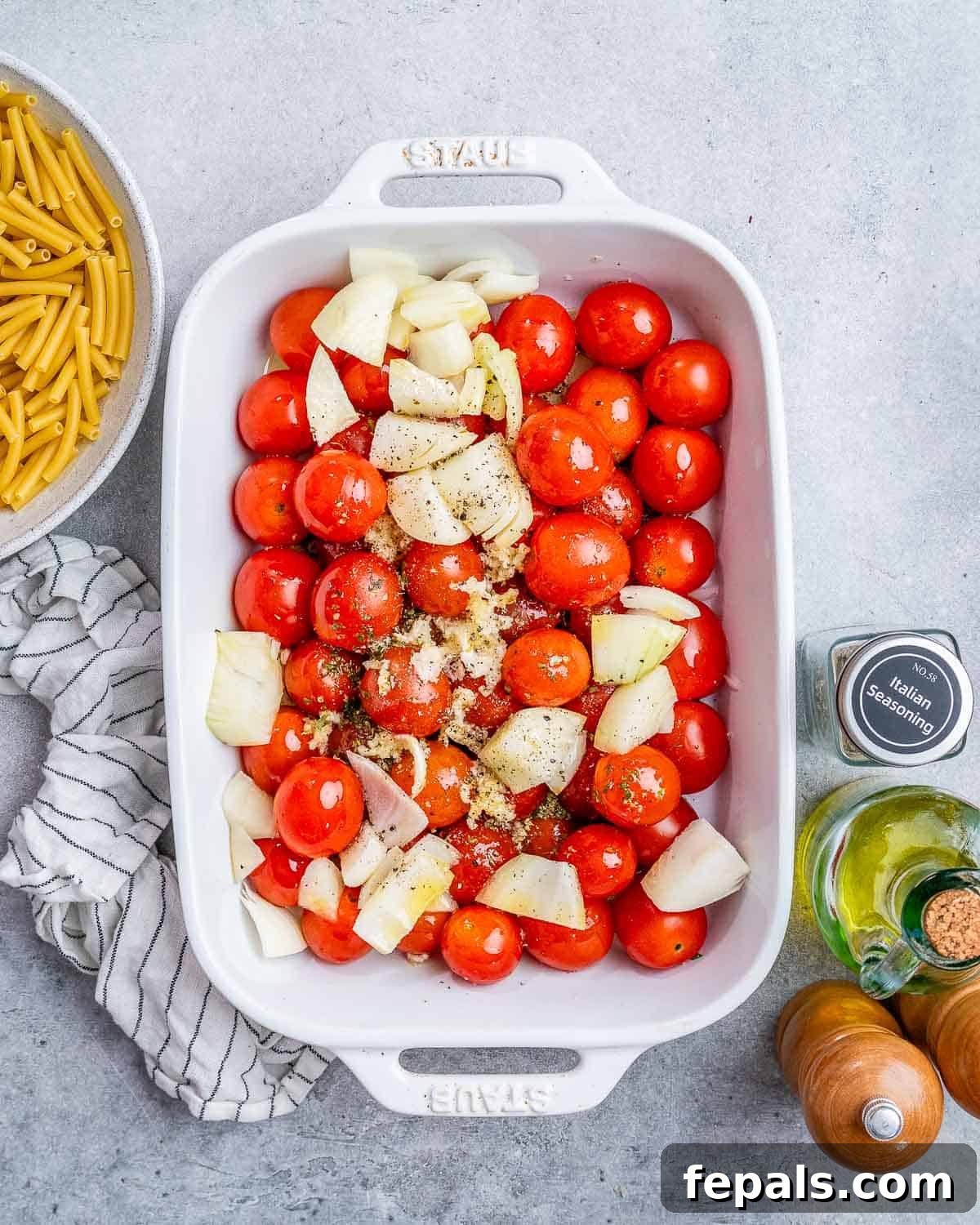 Ultimate Cheesy Baked Ziti 5 Fresh cherry tomatoes and diced onions arranged in a white baking dish, ready for roasting.