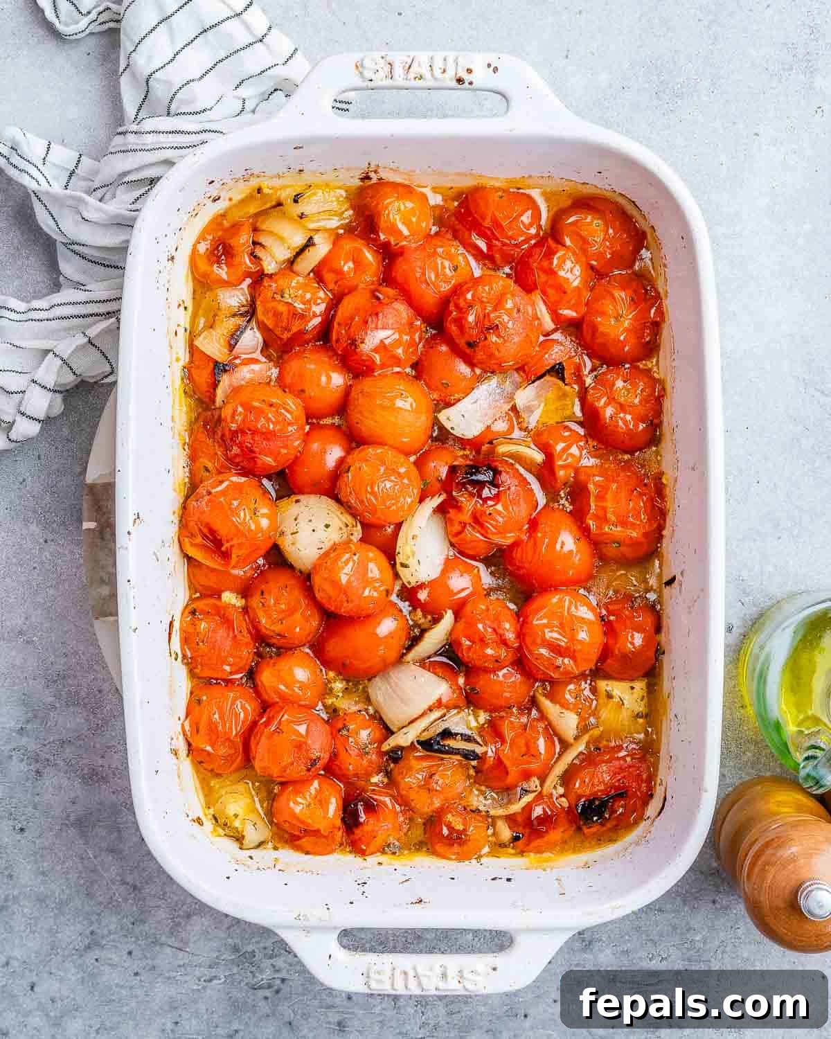 Ultimate Cheesy Baked Ziti 6 Roasted cherry tomatoes and onions, softened and slightly charred, resting in a white casserole dish after baking.