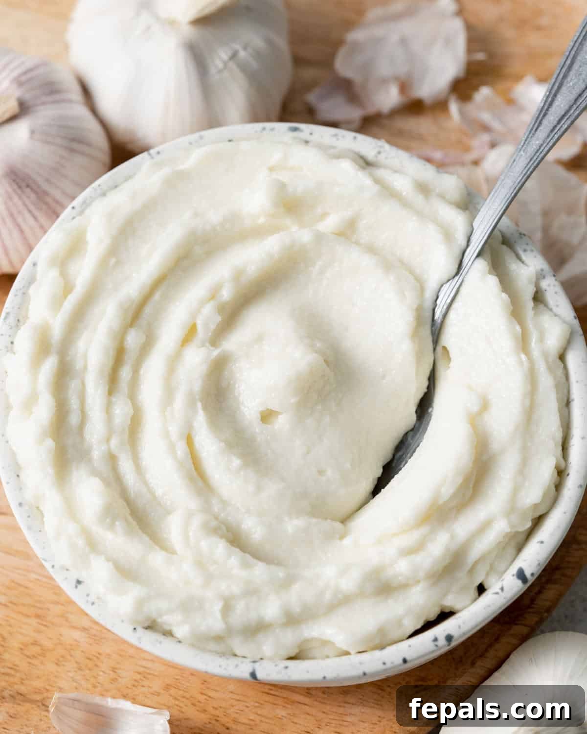Fluffy Lebanese Garlic Dip 2 A beautifully presented bowl of creamy white Lebanese garlic sauce (Toum) with a spoon, ready to be enjoyed.