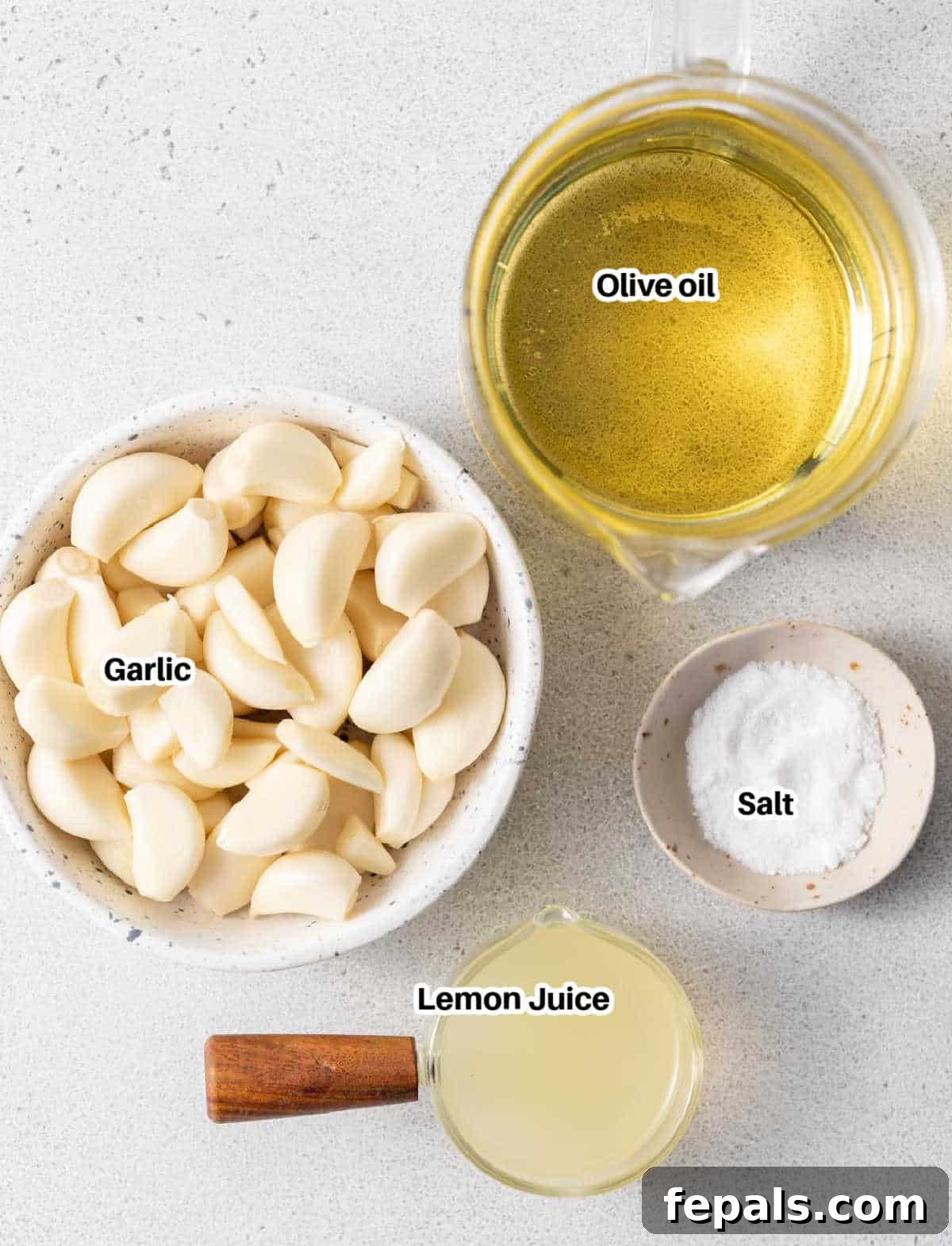 Fluffy Lebanese Garlic Dip 3 A selection of fresh garlic cloves, neutral oil, and lemons arranged on a surface, ready for making homemade garlic sauce.