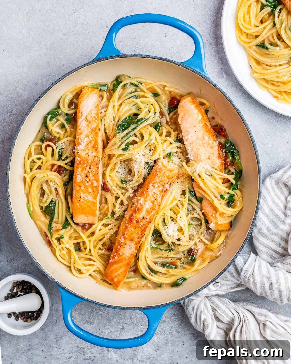 Decadent Salmon Alfredo 2 A pot with pasta, cream sauce, and fried salmon on top.
