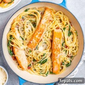 Decadent Salmon Alfredo 11 A blue skillet with spaghetti and 3 salmon fillets.