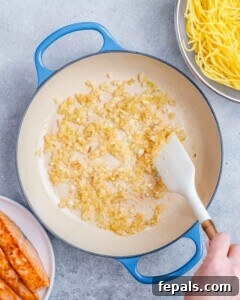 Decadent Salmon Alfredo 13 Stirring garlic in a blue pot.