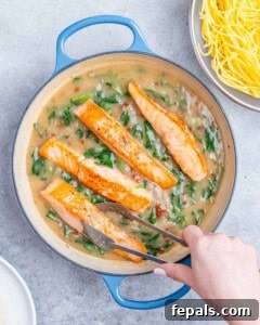 Decadent Salmon Alfredo 16 Adding salmon to a pot with a creamy spinach mixture.