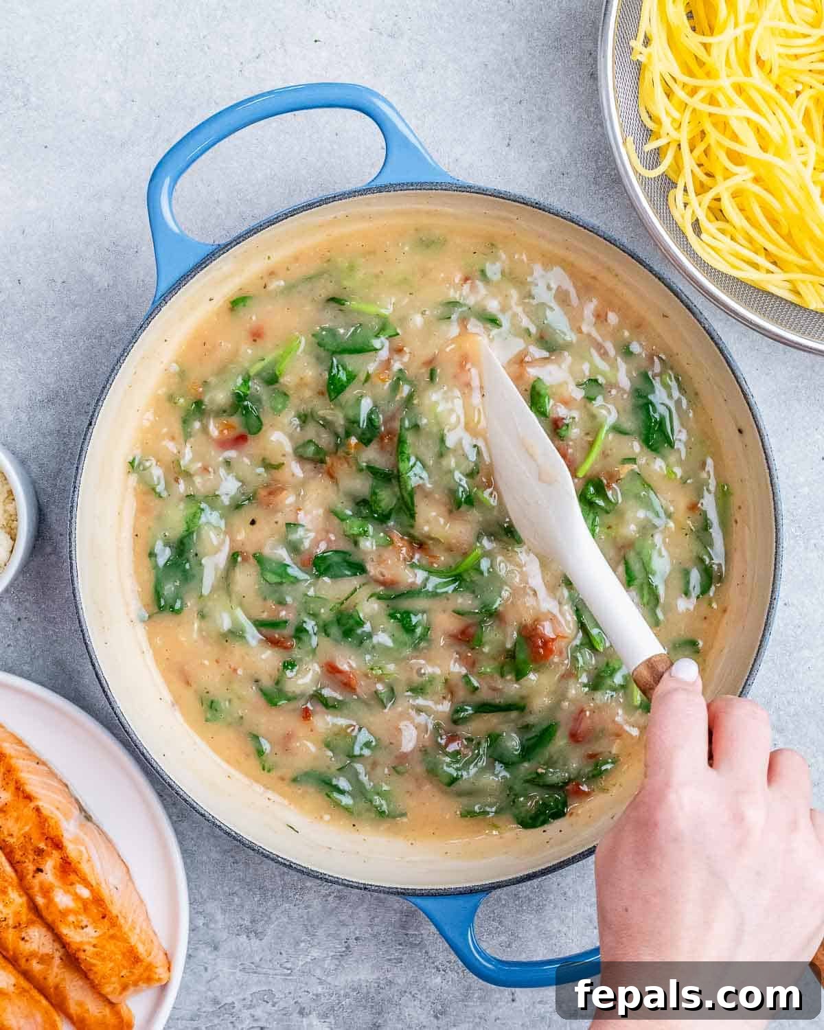 Decadent Salmon Alfredo 6 Stirring cream mixture in a pot.
