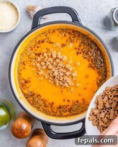 Pouring pasta into a pot of soup.