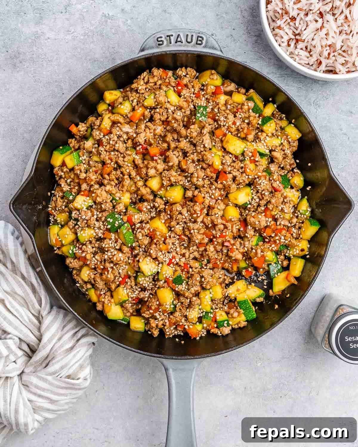 A vibrant Ground Turkey Stir Fry with colorful vegetables in a large skillet, ready to be served, set on a modern gray background.