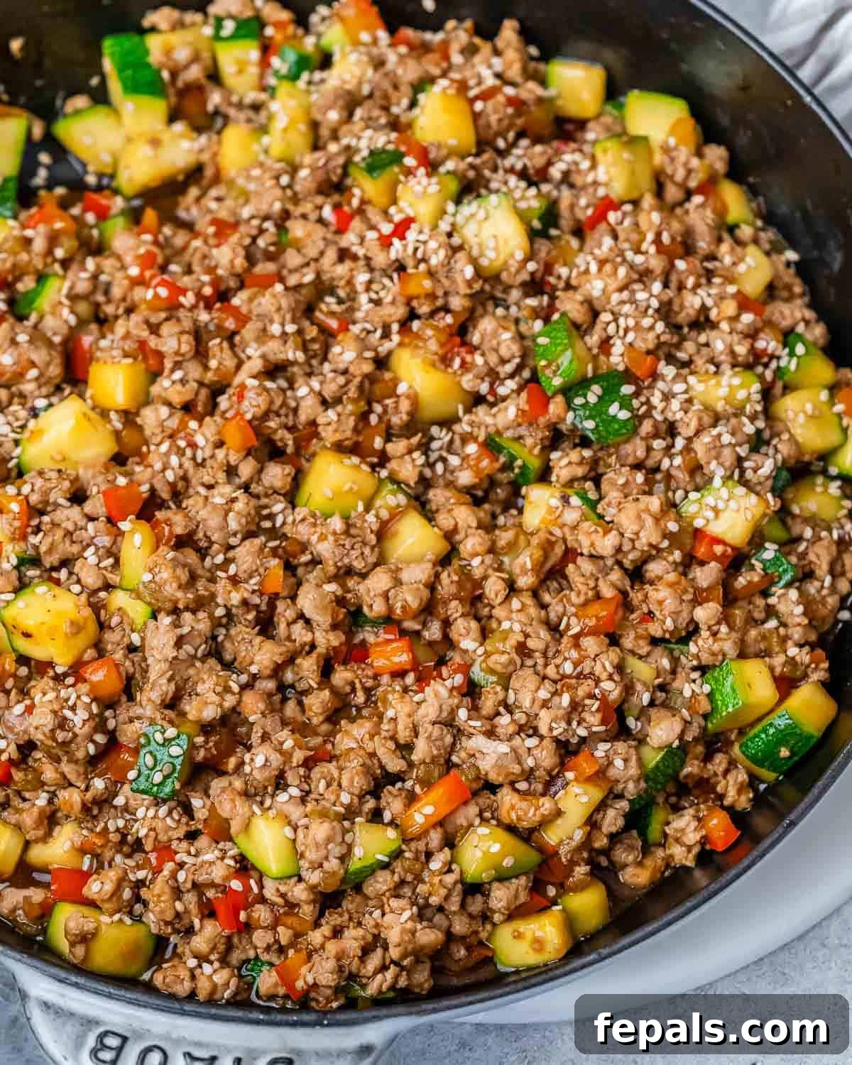 The Ground Turkey Stir Fry served over rice in an individual bowl, garnished with green onions and sesame seeds.