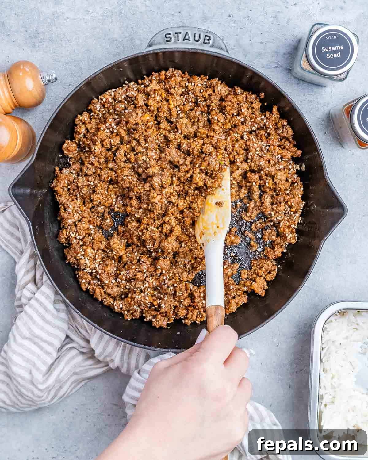 Hearty Beef & Rice Medley 8 Stirring ground beef in a skillet with a white spatula.