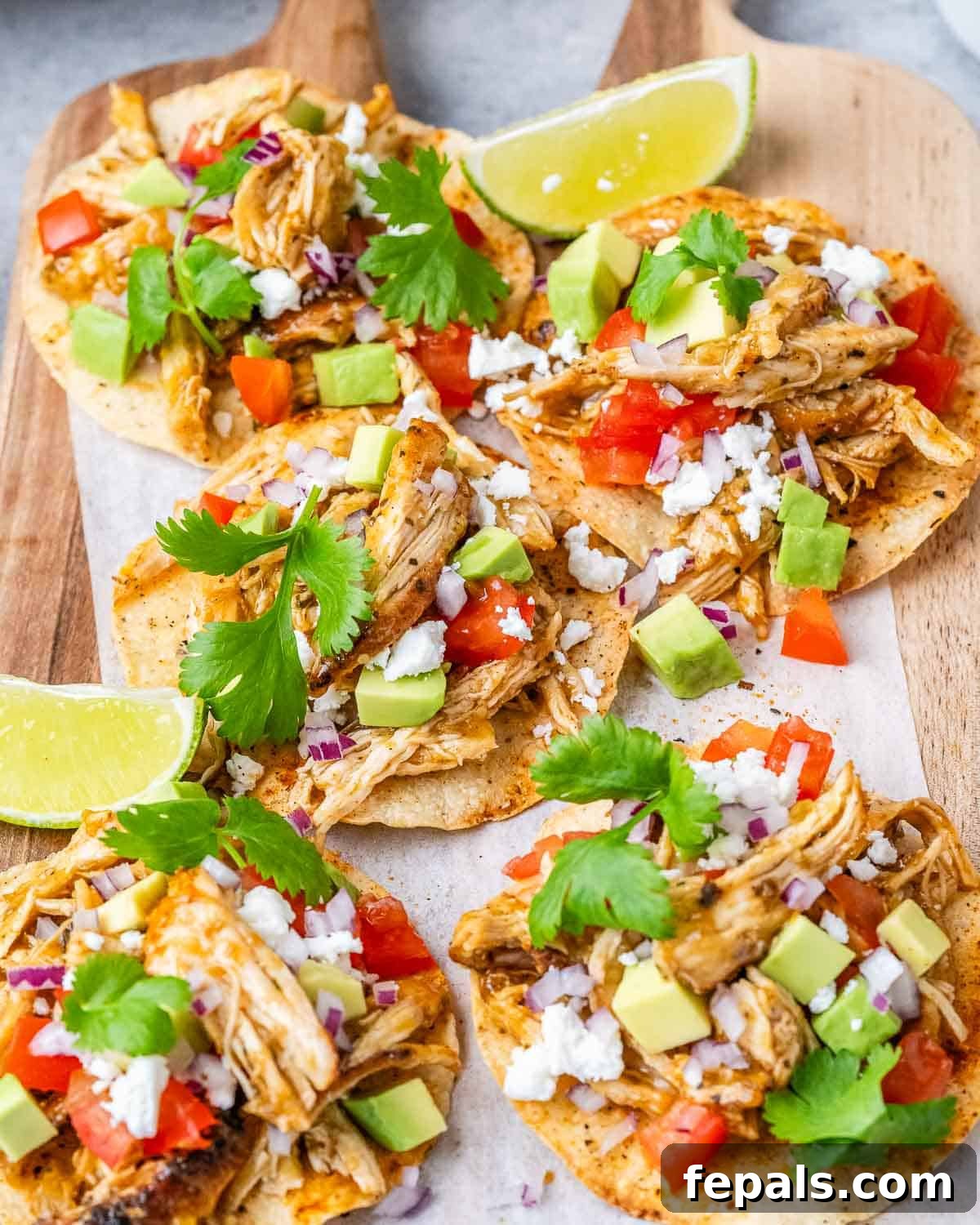 Fiesta Chicken Tostadas 2 Crispy chicken tostadas on a wooden cutting board, garnished with fresh cilantro and chopped avocados. A vibrant and appealing meal.