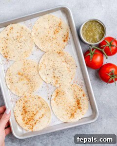 Fiesta Chicken Tostadas 14 Six corn tortillas sprinkled with seasoning on a baking sheet.