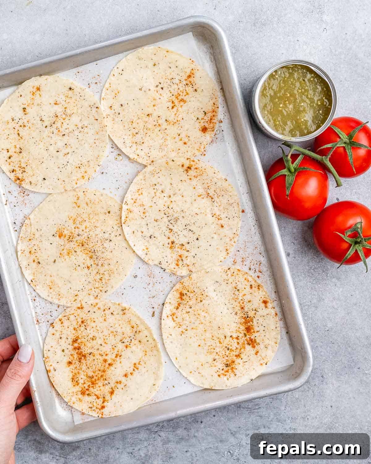 Fiesta Chicken Tostadas 6 Twelve small corn tortillas arranged on a baking sheet, lightly sprayed with olive oil and seasoned with taco spices, ready for baking.